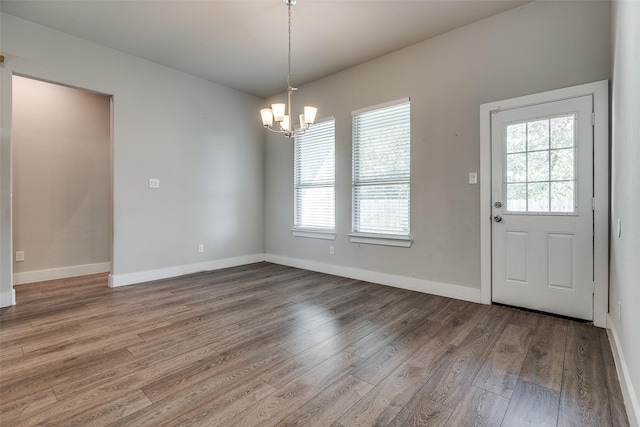 unfurnished dining area with hardwood / wood-style floors and a notable chandelier