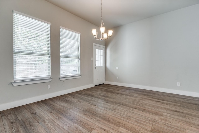 unfurnished dining area with hardwood / wood-style flooring, plenty of natural light, and an inviting chandelier