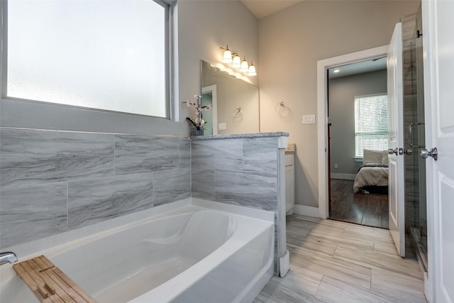 bathroom featuring vanity, wood-type flooring, and a bath