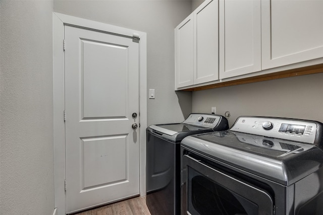 laundry area featuring cabinets, light hardwood / wood-style flooring, and washer and dryer