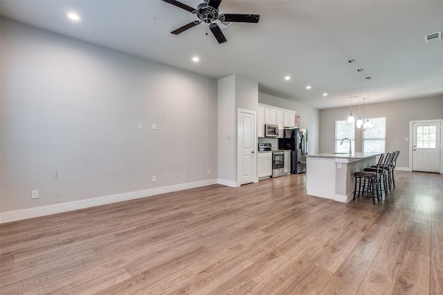 kitchen with white cabinetry, sink, a kitchen island with sink, appliances with stainless steel finishes, and light wood-type flooring