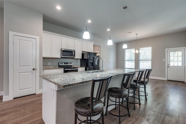 kitchen featuring pendant lighting, a kitchen island with sink, hardwood / wood-style floors, and stainless steel appliances