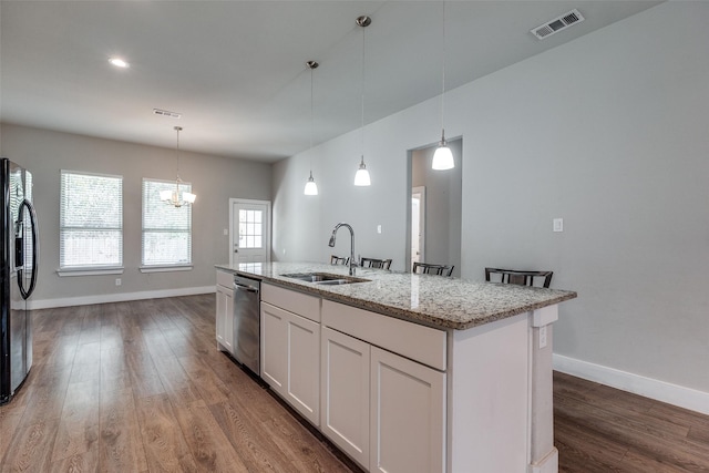 kitchen with appliances with stainless steel finishes, sink, hardwood / wood-style flooring, white cabinetry, and an island with sink