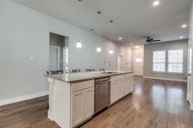 kitchen with hardwood / wood-style floors, a center island with sink, stainless steel dishwasher, ceiling fan, and white cabinetry