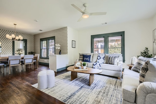 living room with dark hardwood / wood-style flooring and ceiling fan with notable chandelier