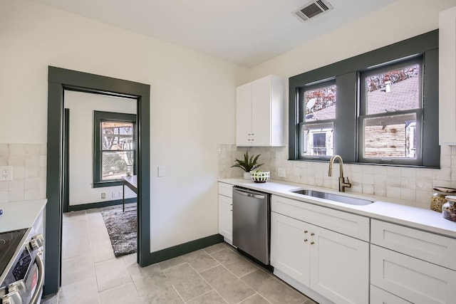 kitchen with appliances with stainless steel finishes, tasteful backsplash, sink, white cabinets, and light tile patterned flooring