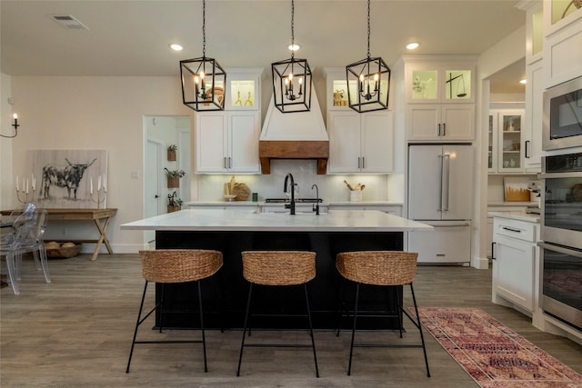 kitchen with appliances with stainless steel finishes, a center island with sink, and white cabinetry