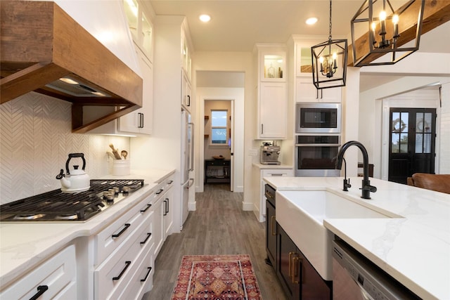 kitchen featuring dark hardwood / wood-style flooring, stainless steel appliances, sink, white cabinets, and hanging light fixtures