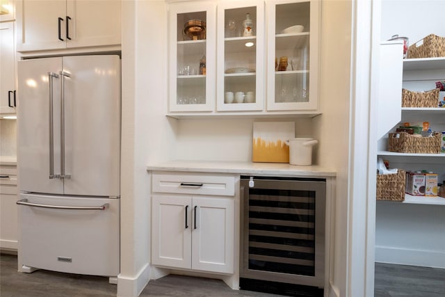 bar featuring dark wood-type flooring, white cabinets, wine cooler, light stone countertops, and high end fridge