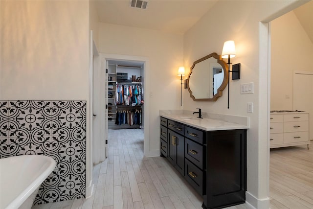 bathroom with hardwood / wood-style floors, vanity, and a washtub