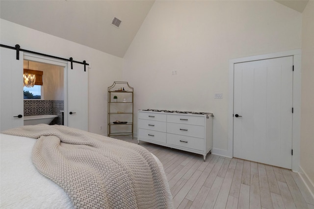 bedroom with a closet, a barn door, high vaulted ceiling, and light hardwood / wood-style flooring