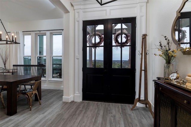 entryway featuring french doors, light hardwood / wood-style flooring, and a notable chandelier