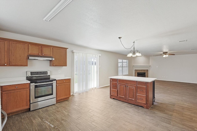 kitchen featuring light hardwood / wood-style floors, decorative light fixtures, stainless steel electric stove, a kitchen island, and ceiling fan with notable chandelier