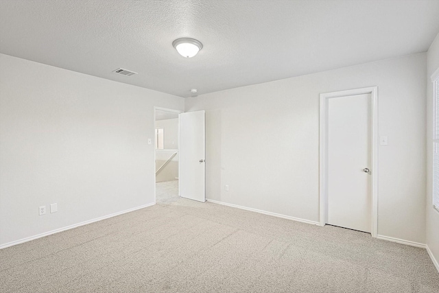 spare room with light carpet and a textured ceiling