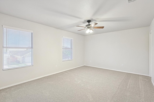 empty room featuring a wealth of natural light, carpet, and ceiling fan