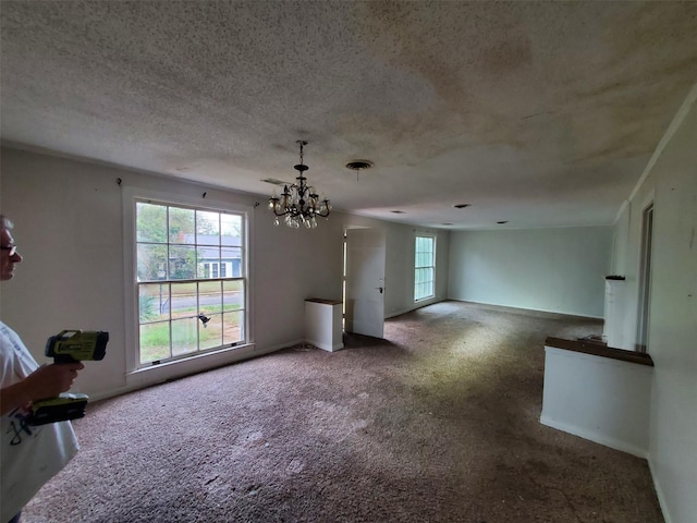 unfurnished living room with carpet, a textured ceiling, and a notable chandelier