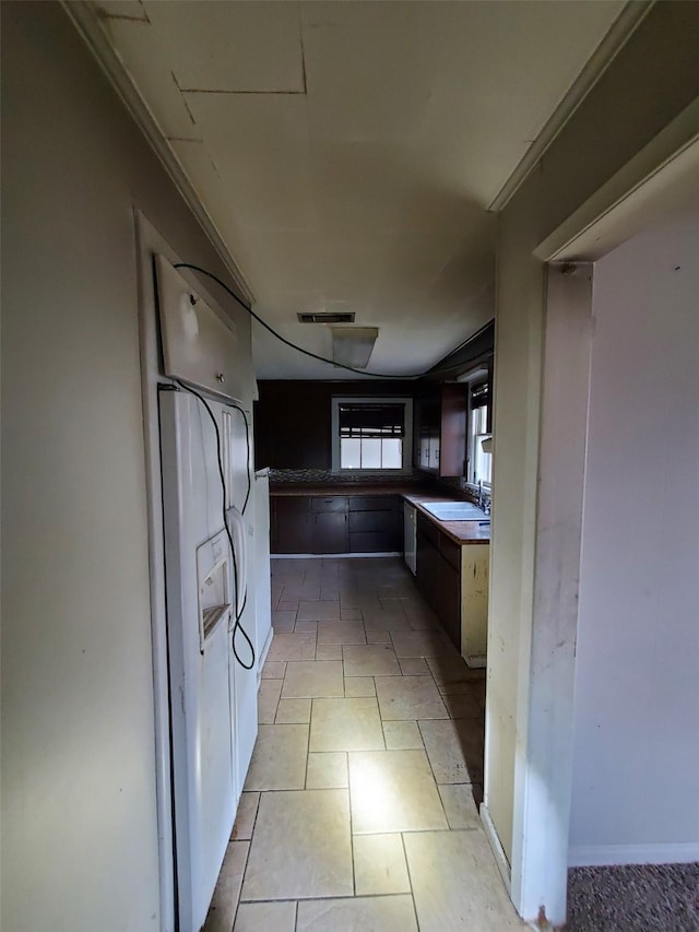 kitchen with dishwashing machine, sink, light tile patterned flooring, and ornamental molding