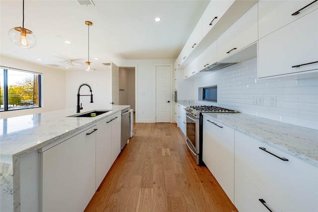 kitchen featuring stainless steel appliances, sink, light hardwood / wood-style flooring, white cabinets, and hanging light fixtures