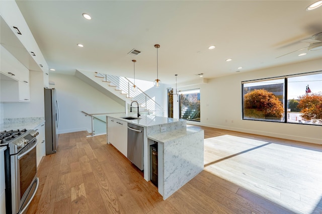 kitchen featuring pendant lighting, white cabinets, sink, an island with sink, and appliances with stainless steel finishes