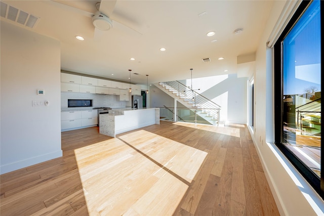 unfurnished living room with ceiling fan and light hardwood / wood-style floors