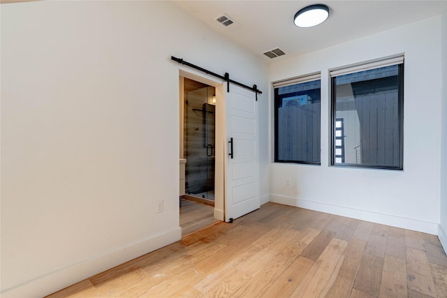 spare room with light wood-type flooring and a barn door