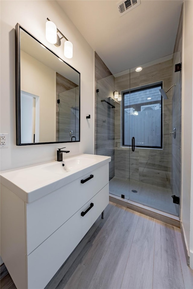 bathroom with hardwood / wood-style floors, vanity, and a shower with door