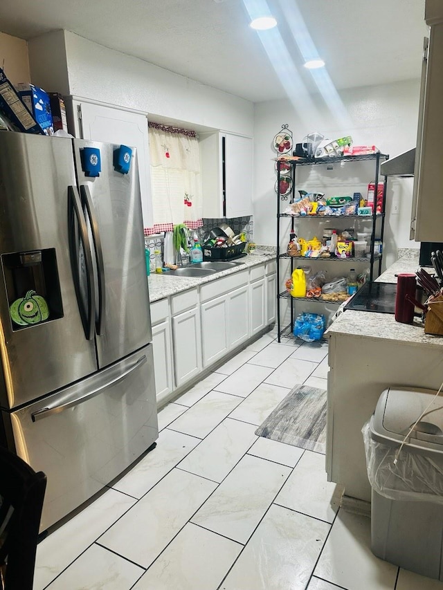 kitchen featuring white cabinets, decorative backsplash, sink, and stainless steel refrigerator with ice dispenser