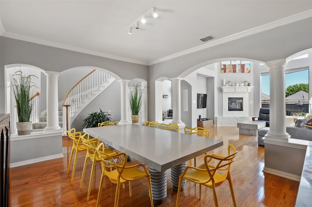 dining area with hardwood / wood-style floors, crown molding, a fireplace, and rail lighting