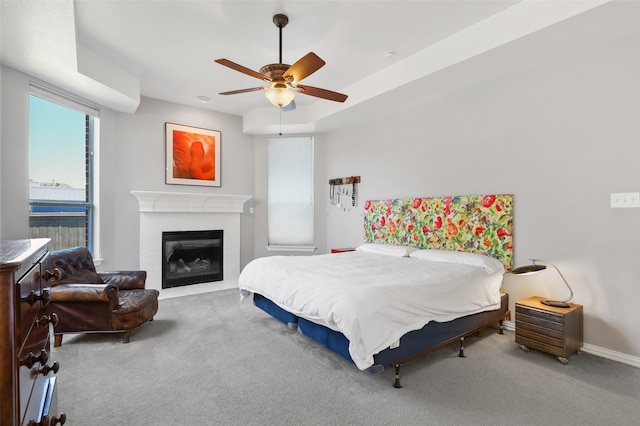 carpeted bedroom featuring a tile fireplace and ceiling fan