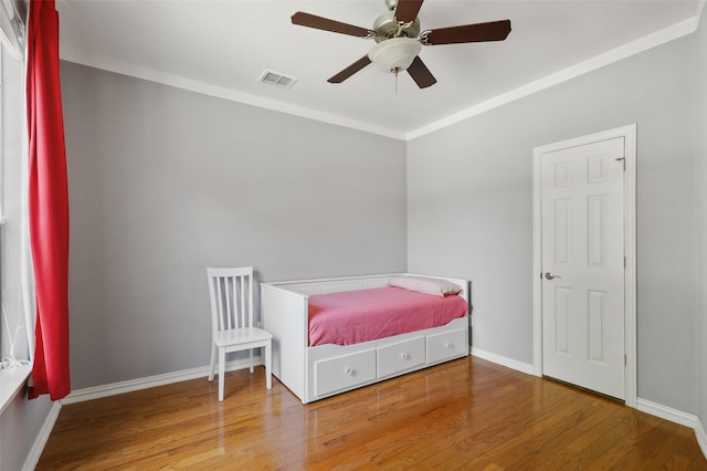 bedroom featuring hardwood / wood-style floors, ceiling fan, and ornamental molding