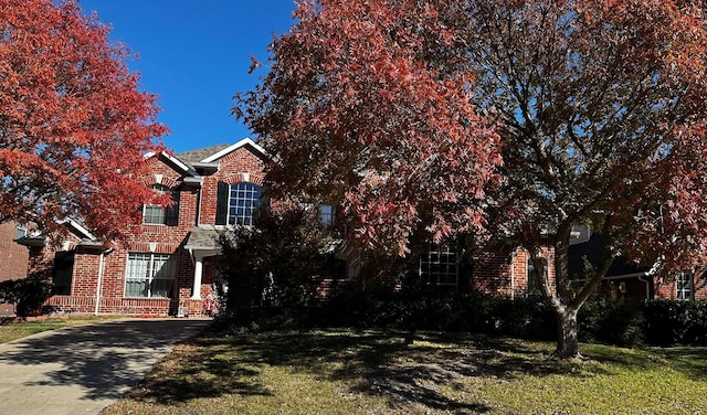 view of property hidden behind natural elements featuring a front lawn