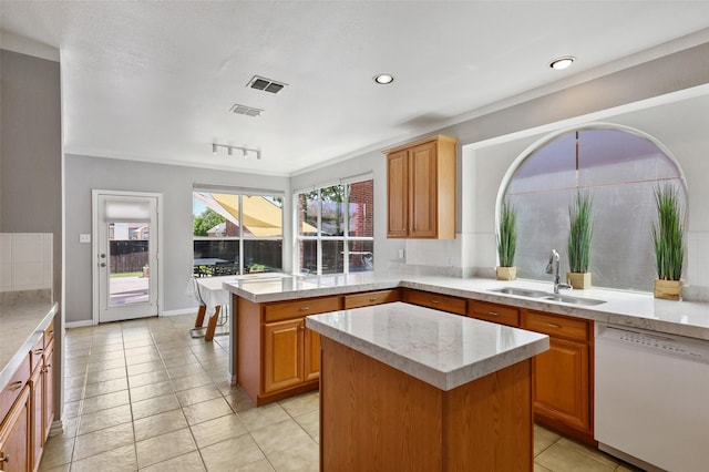 kitchen featuring dishwasher, light tile patterned floors, a kitchen island, and sink