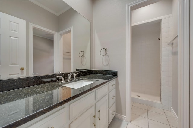 bathroom featuring tile patterned floors, vanity, a tile shower, and ornamental molding