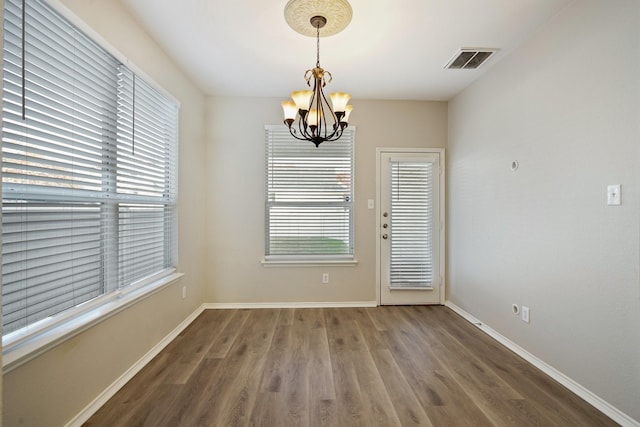 empty room with dark hardwood / wood-style floors and a notable chandelier