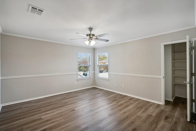 empty room with ceiling fan, ornamental molding, and dark wood-type flooring