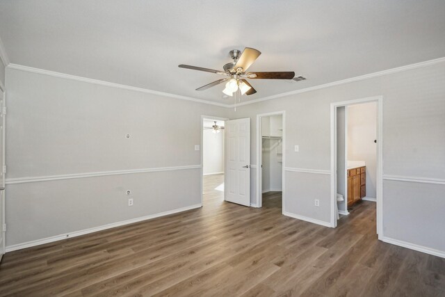 unfurnished bedroom with a spacious closet, ceiling fan, dark hardwood / wood-style floors, a closet, and ornamental molding