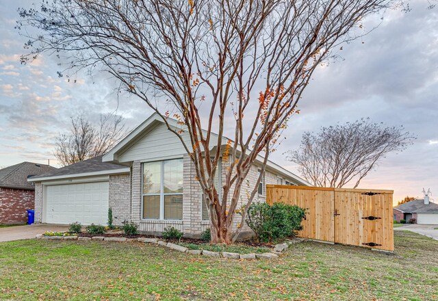 view of side of property with brick siding, a lawn, concrete driveway, and a garage