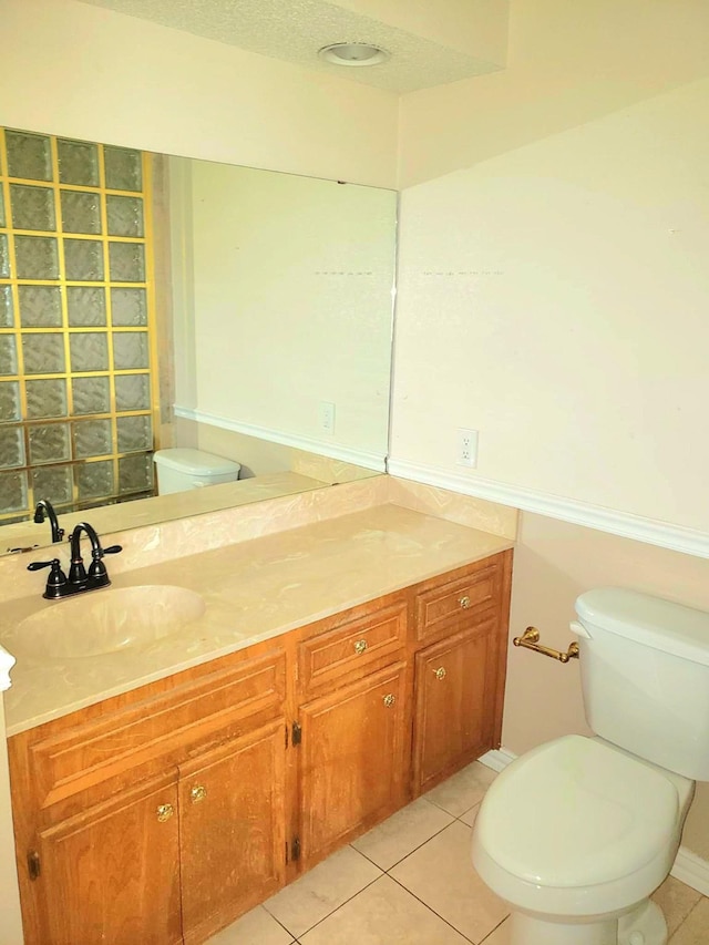 bathroom with tile patterned floors, vanity, a textured ceiling, and toilet