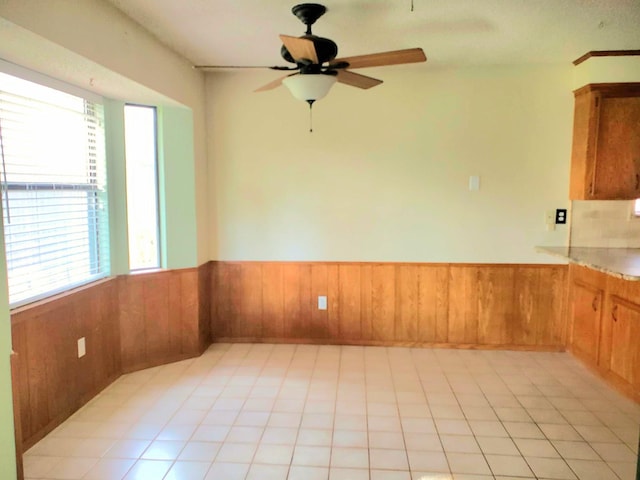 tiled spare room featuring wooden walls and ceiling fan