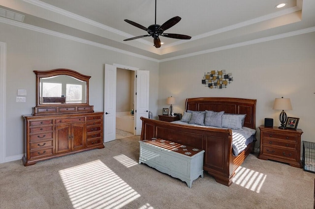 bedroom with ceiling fan, light colored carpet, a raised ceiling, ensuite bath, and crown molding