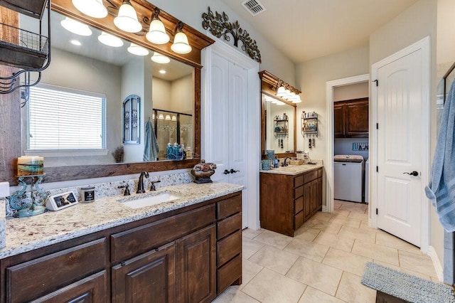 bathroom featuring a shower with door, tile patterned flooring, vanity, and washer / clothes dryer