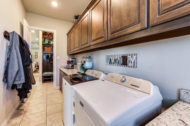 laundry area with light tile patterned floors, cabinets, and washer and dryer