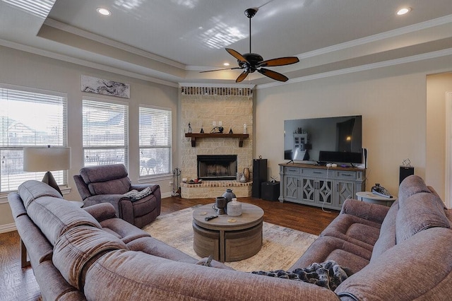 living room with ceiling fan, wood-type flooring, a tray ceiling, and ornamental molding