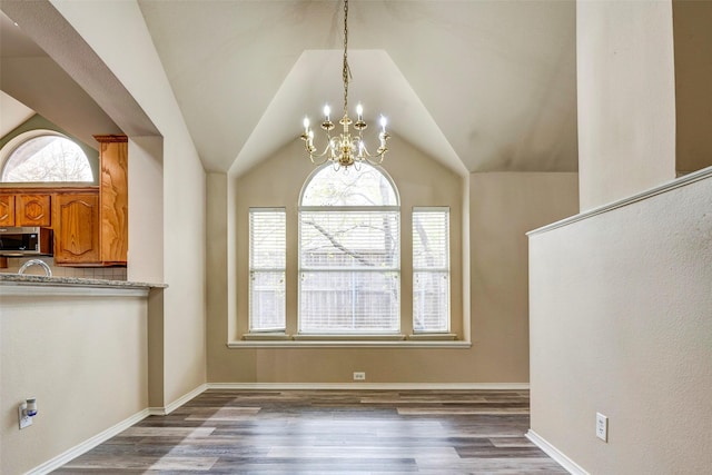 unfurnished dining area featuring plenty of natural light, dark hardwood / wood-style floors, and vaulted ceiling