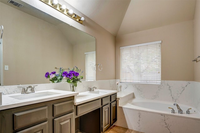 bathroom featuring a textured ceiling, a bathing tub, vanity, and lofted ceiling