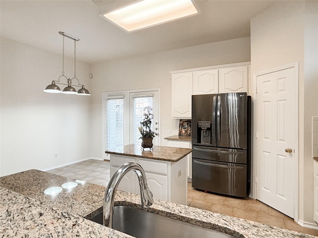 kitchen with white cabinets, a center island, stainless steel fridge, and light stone counters