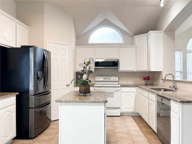 kitchen featuring appliances with stainless steel finishes, sink, white cabinets, decorative backsplash, and a center island