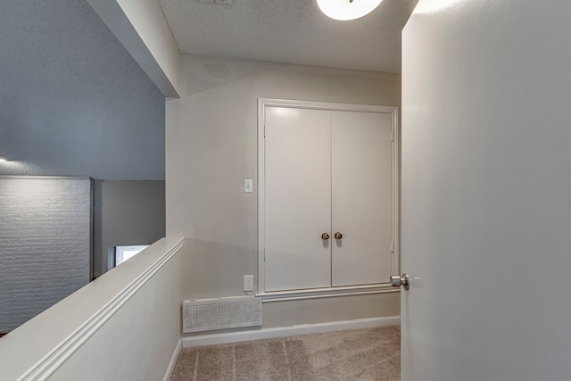 corridor with light colored carpet and a textured ceiling