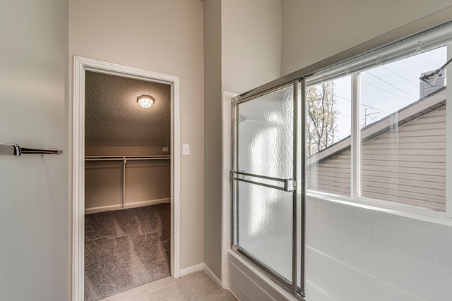 bathroom featuring shower / bath combination with glass door, a textured ceiling, and tile patterned flooring