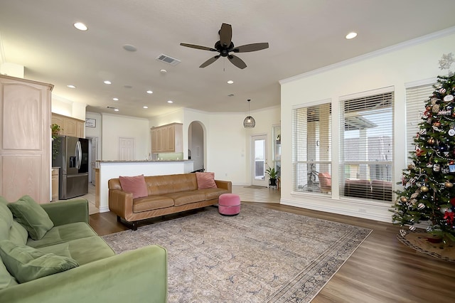 living room featuring hardwood / wood-style flooring, crown molding, and ceiling fan